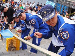 真剣な表情で「流しそうめん」の競技に挑む出場者たち