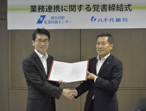 握手を交わす岸本所長（左）と長岡取締役