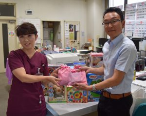 玩具を手渡す高木代表（右）と河本所長