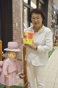 店舗の前で自作の人形と石井さん