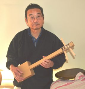 工作三味線を構える小松社長