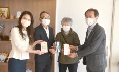 田川代表理事に寄付金を手渡す寄付者（左3人）＝記者が現地撮影