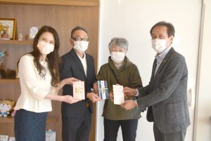 田川代表理事に寄付金を手渡す寄付者（左3人）＝記者が現地撮影