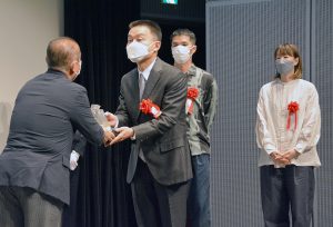 本村市長から表彰を受ける鎌田氏と、新人賞の岸さん、中井さん（右）